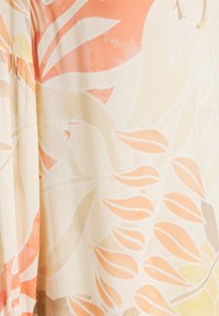 Tkanina w delikatne duże wzory kwiatowe i liściaste w odcieniach brzoskwiniowym, beżowym i kremowym, z marszczeniami po lewej stronie.