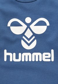 Blå bomulds-t-shirt med et stort hvidt logo med abstrakte former og ordet "hummel" i fede, afrundede bogstaver.