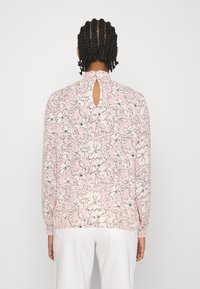 Lätt, rosa blus med blommönster, samlad halsringning och nyckelhålsdetalj bak. Långa ärmar med elastiska manschetter.