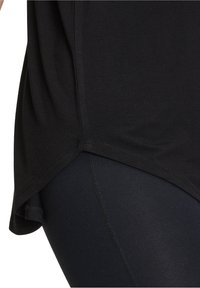 Svart kortärmad topp med rundad nederkant, tillverkad av mjukt material, tillsammans med svarta leggings med en slät yta och sömdetaljer.