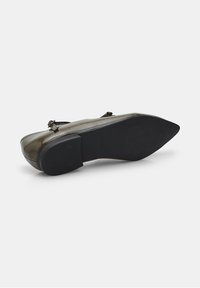 Zapato de charol marrón con punta afilada, diseño minimalista, pequeño detalle de hebilla y suela de goma negra texturizada.
