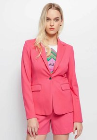 Roze blazer met gestructureerd ontwerp, voorzien van een voeringssluiting, twee zakken en een gladdige stoftextuur, gecombineerd met bijpassende shorts.