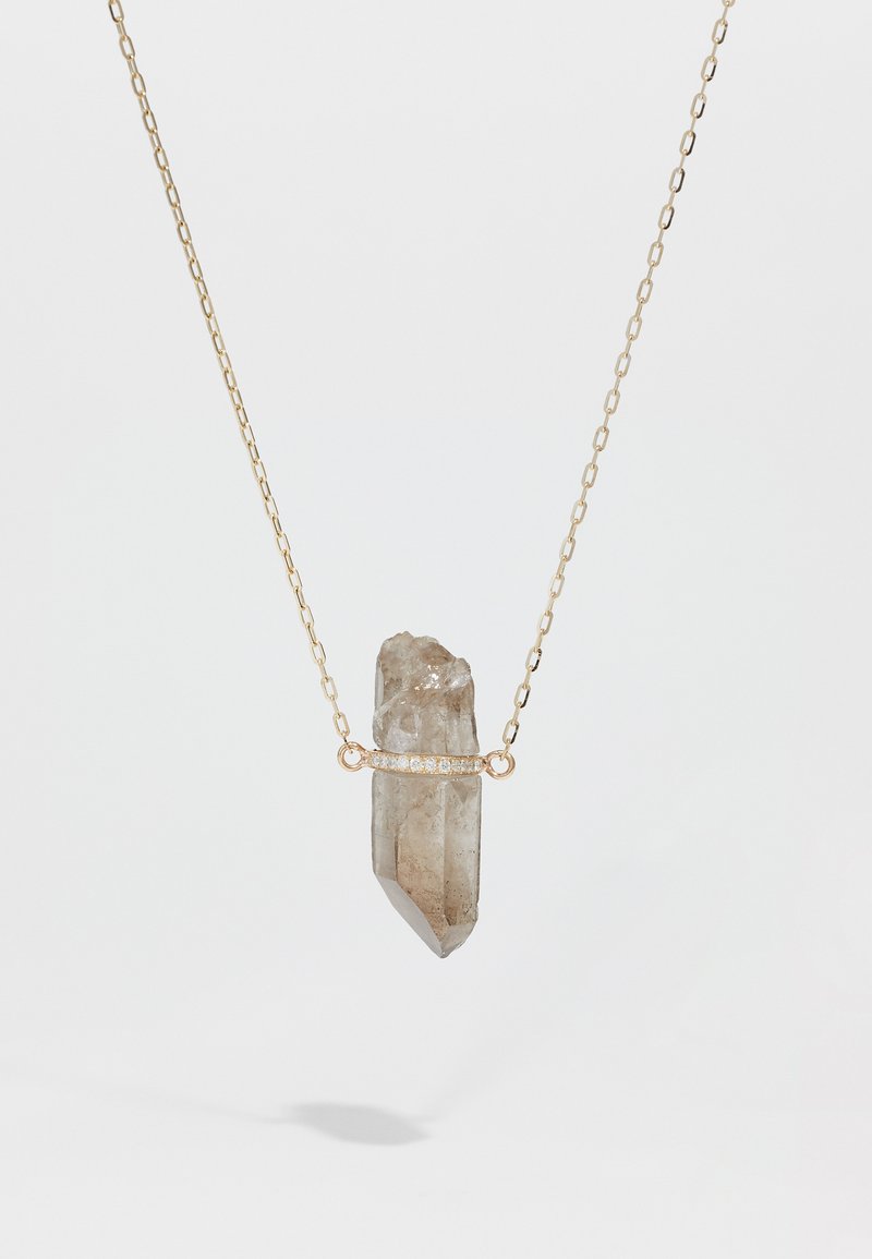 Guld kæde med en rå, klar kvarts krystal vedhæng, delvist indpakket med et fint bånd af små diamanter.