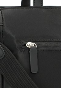 Borsa tote in tessuto nero con una tasca con zip e un tirante in argento, cinturino testurizzato e superficie esterna liscia.