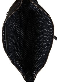 Wnętrze czarnej torebki na ramię, wyłożone białą tkaniną w kropki, z otwartym zamkiem błyskawicznym i małą wewnętrzną kieszenią na zamek z boku.