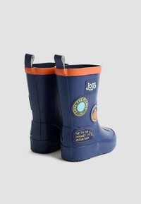 Botas de goma de lluvia en color navy con un ribete naranja. Presentan varias insignias circulares con diseños y texto. Suela de alta tracción y lengüetas de agarre.