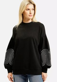 Czarny sweter z długimi, balonowymi rękawami, ozdobiony białymi falistymi wzorami. Wykonany z miękkiej, teksturowanej tkaniny z okrągłym dekoltem.