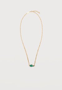 Χρυσή αλυσίδα με κρεμαστό σε σχήμα μικρού πράσινου κροκοδείλου από πέτρες σε λευκό φόντο.