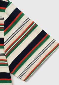 Tissu rayé avec des couleurs alternées : crème, marine, vert, rouge et noir. Il présente une texture douce et une coupe en diagonale à la manche.