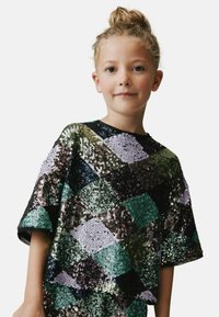Seyferad T-shirt med en lapptäckesdesign i gröna, lila och svarta färger; korta ärmar och rund halsringning.