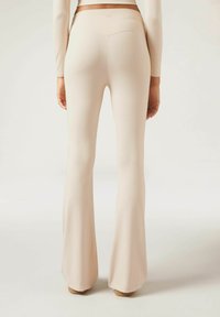 Pantalons évasés nus en tissu extensible, avec une taille haute et une texture lisse, dotés d'un discret logo au dos.