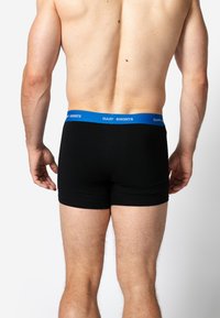 Zwarte boxer briefs met een blauwe elastische tailleband met de tekst "HAPPY SHORTS". Glad materiaal, strakke pasvorm en lengte tot halverwege de dij.