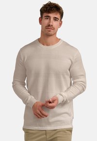 Krém színű kötött pulóver textur�ált vízszintes csíkokkal, kerek nyakkal és bordázott mandzsettákkal. Az anyag puha, könnyű és hétköznapi viseletre alkalmas.