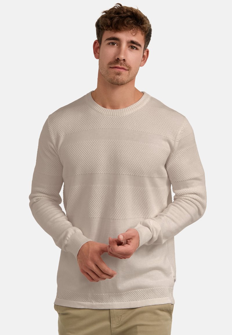 Krém színű kötött pulóver texturált vízszintes csíkokkal, kerek nyakkal és bordázott mandzsettákkal. Az anyag puha, könnyű és hétköznapi viseletre alkalmas.