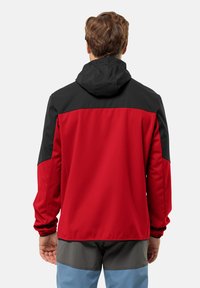 Veste rouge et noire avec capuche, présentant une texture lisse, un design bicolore, des poignets élastiques et une construction légère.