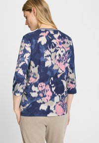 Marineblaues Blumen-Pullover mit Dreiviertelärmeln, der pinke und hellgraue Rosenmuster aufweist. Weicher Stoff mit rundem Ausschnitt und subtiler Textur.