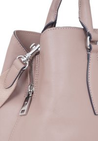 Sac à main en cuir rose clair avec une texture lisse, doté de fermetures éclair en argent, d'une bandoulière détachable et d'arêtes sombres contrastantes.