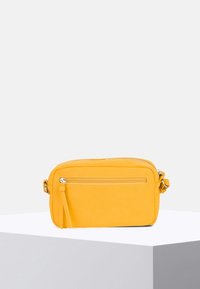 Borsa a tracolla gialla in pelle con una superficie liscia, dotata di una tasca frontale con zip e tracolla regolabile. Forma rettangolare compatta.