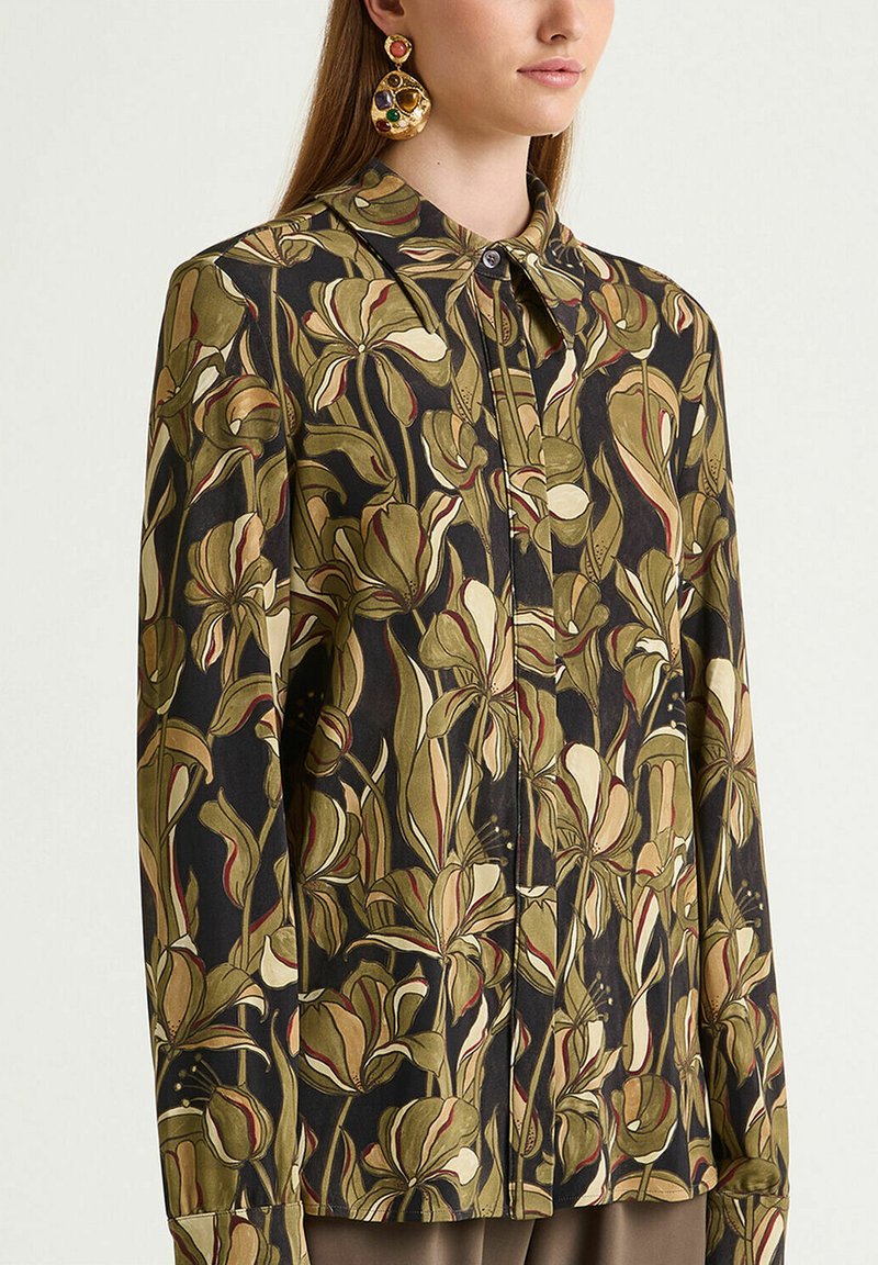Langärmlige Bluse aus dunklem Stoff mit großen grünen und cremefarbenen Blumenmustern, vorne mit Knöpfen und klassischem Kragen.