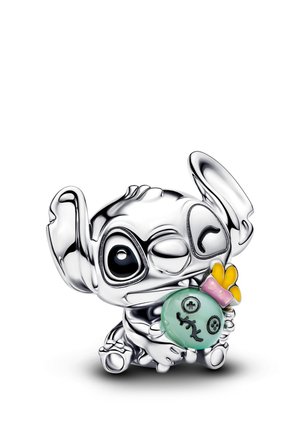 Piccola figurina d'argento di un personaggio con grandi orecchie che tiene una bambola verde con dettagli cuciti e un accessorio rosa e giallo.