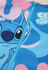 Grenouillère bleue pour enfants avec un personnage de dessin animé. Elle possède une fermeture éclair intégrale à l'avant et des motifs colorés de formes roses et bleues.