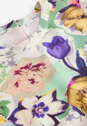 Blusa con motivo floreale in tessuto leggero. Presenta fiori viola, gialli e rosa su uno sfondo verde e crema. Collo rotondo.