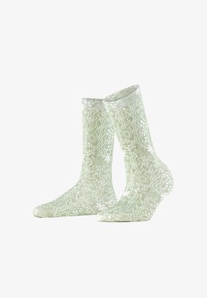 Lichtgroene sokken met witte bloemmotieven en golvende lijnen, staand naast elkaar weergegeven op een witte achtergrond.