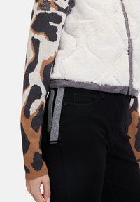 Faux-Fur-Jacke mit einer gesteppten Textur in Weiß, mit einem mehrfarbigen Tiermotiv-Ärmel und einem grauen Riemendetail am Saum.