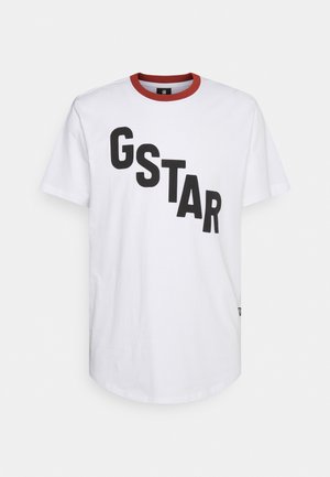 Weißes T-Shirt mit kurzen Ärmeln, rotem Kragen und großen schwarzen Buchstaben, die "GSTAR" diagonal über die Vorderseite schreiben.