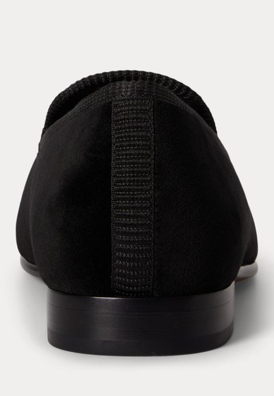 Μαύρο σουέντ γυναικείο παπούτσι με χαμηλό τακούνι, υφασμάτινη θηλιά έλξης στο πίσω μέρος και στρογγυλεμένο περιφερειακό τακουνιού πάνω σε λευκό φόντο.