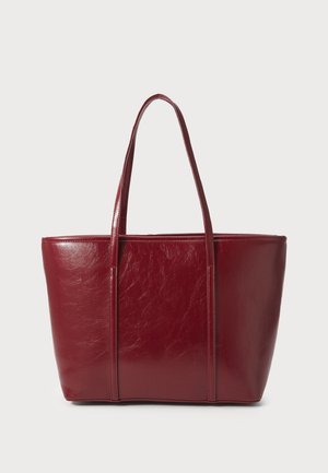 Large glossy dark red leather tote bag with two long handles and a rectangular base on a plain background.