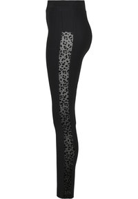 Svarte leggings med et gjennomsiktig panel som har et svart leopardmønster langs de ytre sidene. Glatt tekstur, tettsittende form.
