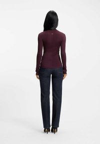 Bordeaux långärmad topp med ribbad textur, figurnära design. Matchad med mörkblå raka jeans, smal passform och högklackade skor.