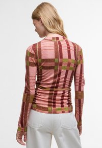 Langärmliges Oberteil in einem rosa-braunen Karomuster mit grünen Akzenten, aus deastischem Stoff mit Raffungen an den Seiten.