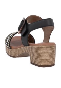 Black and white woven upper sandals with a chunky brown heel. Features an adjustable buckle strap and textured sole. Flat, open-back design.