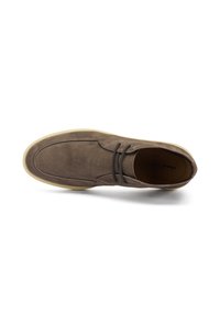 Zapato de ante marrón con puntera redondeada, que presenta detalles de costura sutiles y cordones, montado sobre una suela de goma de color claro.