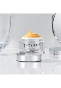 Crema notte anti-invecchiamento Prevage in un barattolo trasparente; consistenza cremosa e giallastra sopra; base argentata; include etichetta "Elizabeth Arden".