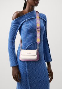 Piccola borsa a mano con schema di colori rosa e bianco, finitura in pelle liscia, dettagli in argento e tracolla regolabile con motivo.