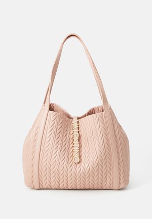 Bolso acolchado de color rosa claro con doble asa para el hombro y un colgante vertical dorado con el logo colgado en el centro del frente.