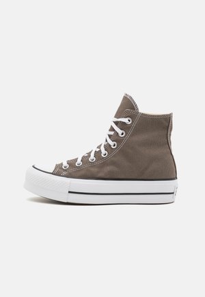 Hochgradige Sneaker aus braunem Canvas mit weißen Schnürsenkeln, Gummispitze und gestreifter Gummisohle. Besitzt eine strukturierte Oberfläche und Nähdetails.