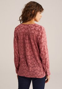 Långärmad blus i dammig ros med texturerat, abstrakt mönster. Mjuk tygkvalitet, avslappnad passform, rynkad bakseam och knappade ärmmuddar.