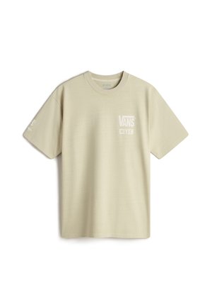 Camiseta de algodón de color beige claro, de mangas cortas y cuello redondo. Presenta el logo blanco de "VANS" en el pecho y en la manga izquierda. Textura suave.