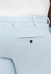 Helle blaue maßgeschneiderte Hosen mit einer glatten, gewebten Textur, einem Rückentasche, gesichert mit einem schwarzen Knopf, und einem slim fit Design.