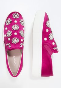 Baskets en satin fuchsia à enfiler avec semelles en caoutchouc blanches, ornées de motifs floraux en perles et strass sur la tige.