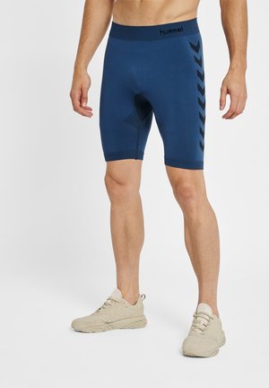 Mænds blå kompressionsshorts med en glat tekstur. Har et sort chevronmønster i siderne og en tætsiddende, elastisk talje.