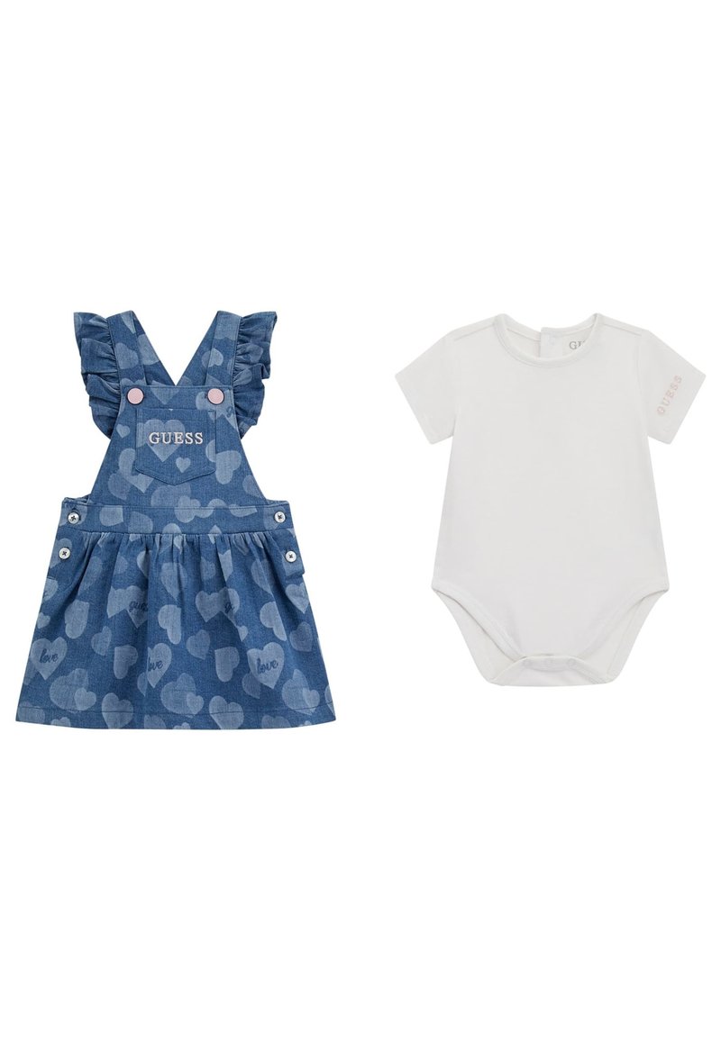 Robe salopette en denim avec des bretelles à volants, motif cœur, et logo "GUESS". Accompagnée d'un body blanc à manches courtes avec un détail de logo.