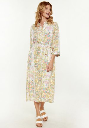 Abito midi con bottoni realizzato in tessuto leggero, con un motivo floreale multicolore, cintura in vita e maniche a tre quarti. Abbinato a sandali bianchi.