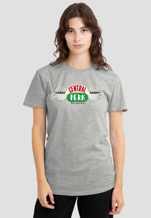 Young woman with long brown hair wearing a grey t-shirt featuring two steaming coffee cups and "Central Perk Friends" logo.