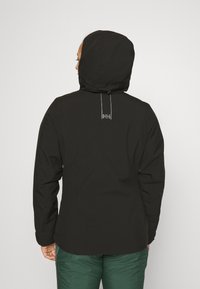 Svart hettejakke med et elegant, minimalistisk design, laget av glatt materiale, med synlig merkevare og en sikker passformjustering.