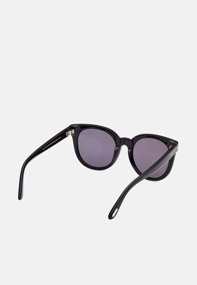 Lunettes de soleil noires en forme d'œil de chat, avec des verres teintés sombres et une monture lisse et brillante. Accent doré subtil sur la tempe.
